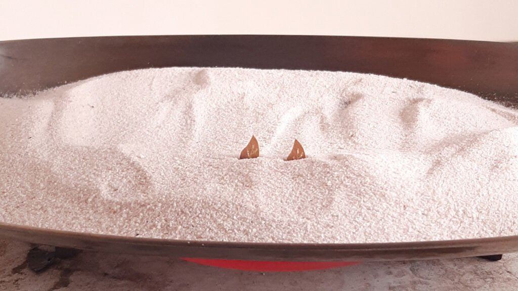 Photo showing the hot sand shading process on petals in a floral marquetry design. A special technique is used to add depth and detail to the wooden petals, highlighting the beauty and realism of the handcrafted design.