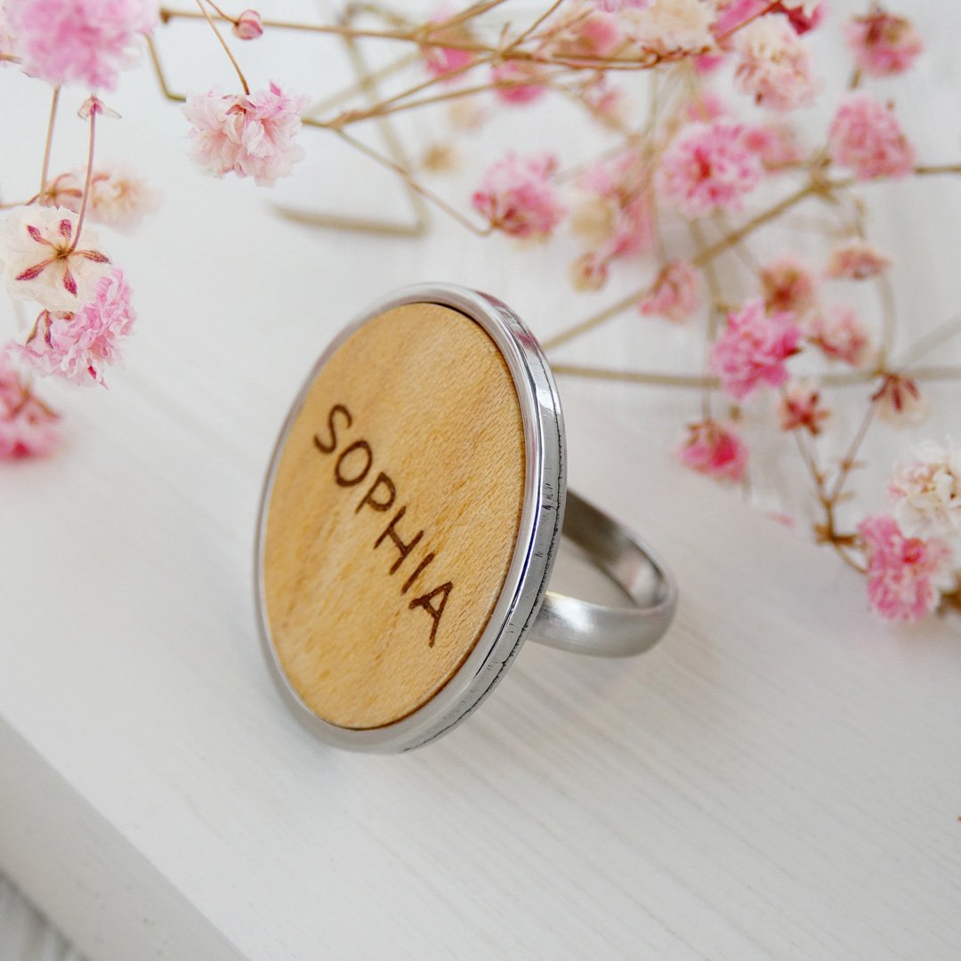 Anillo de madera natural con el nombre de Sophia grabado y base ajustable de acero inoxidable.