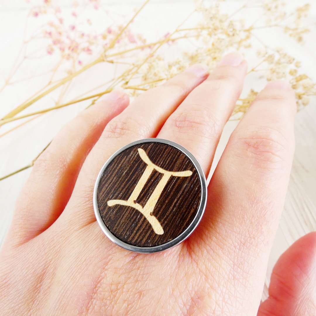Anillo géminis de madera ajustable mostrado en la mano