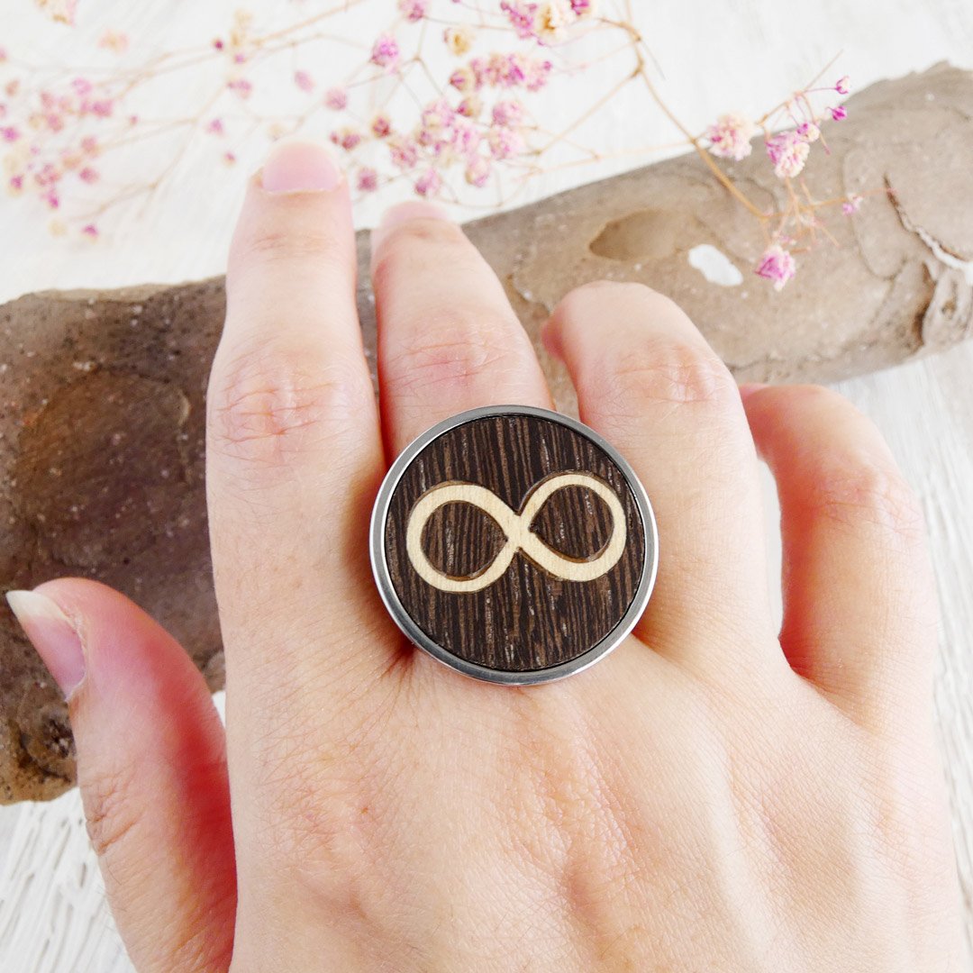 Anillo infinito de madera ajustable puesto en la mano con base de acero inoxidable