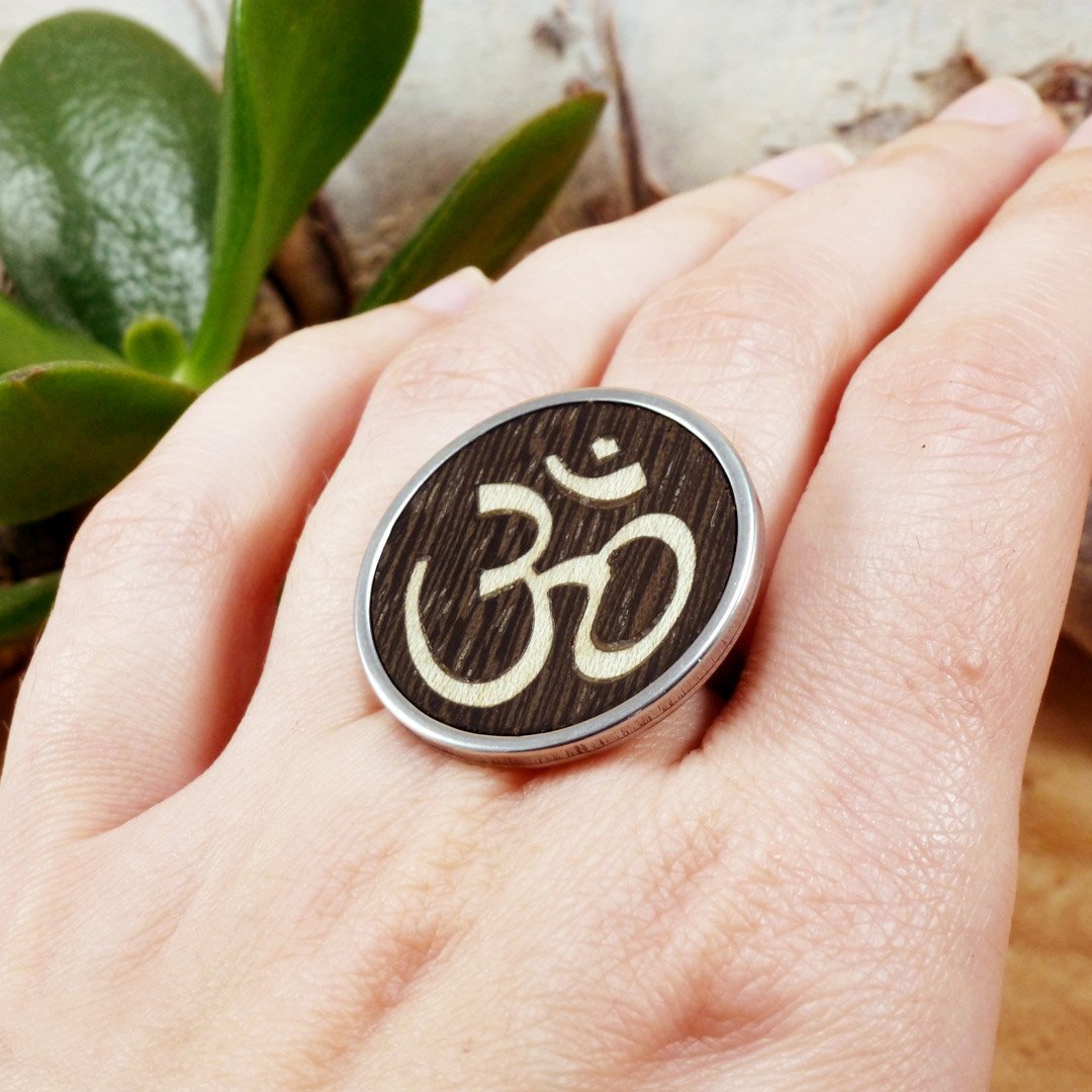 Anillo del símbolo Om hecho a mano con madera natural y acero inoxidable que luce puesto en la mano