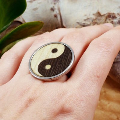 Anillo yin yang de madera ajustable puesto en la mano con base de acero inoxidable