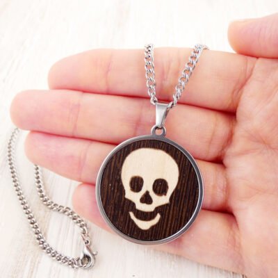 Colgante calavera de madera mostrado en la mano para ver el tamaño real