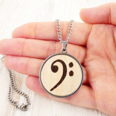 Colgante clave de fa de madera mostrado en la mano para ver el tamaño real