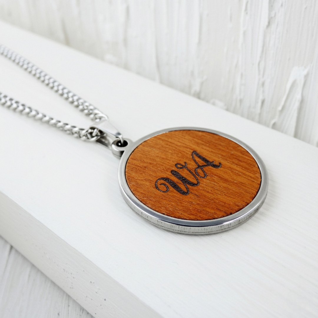 Colgante personalizado con dos iniciales grabadas sobre madera de cebro.