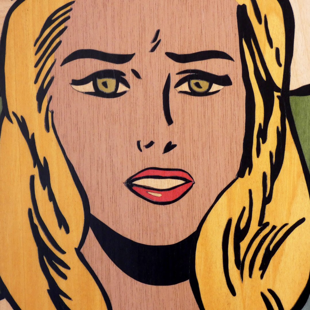 Detalle de la cara de un cuadro decorativo de mujer rubia en marquetería de madera