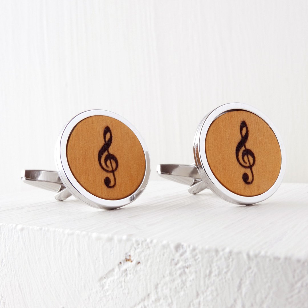 Gemelos de madera de boj con clave de sol grabada y base de acero.