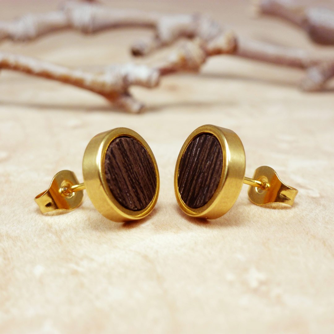 Primer plano de pendientes de botón chapados en oro con madera de wengué oscura: diseño natural hecho a mano para hombres
