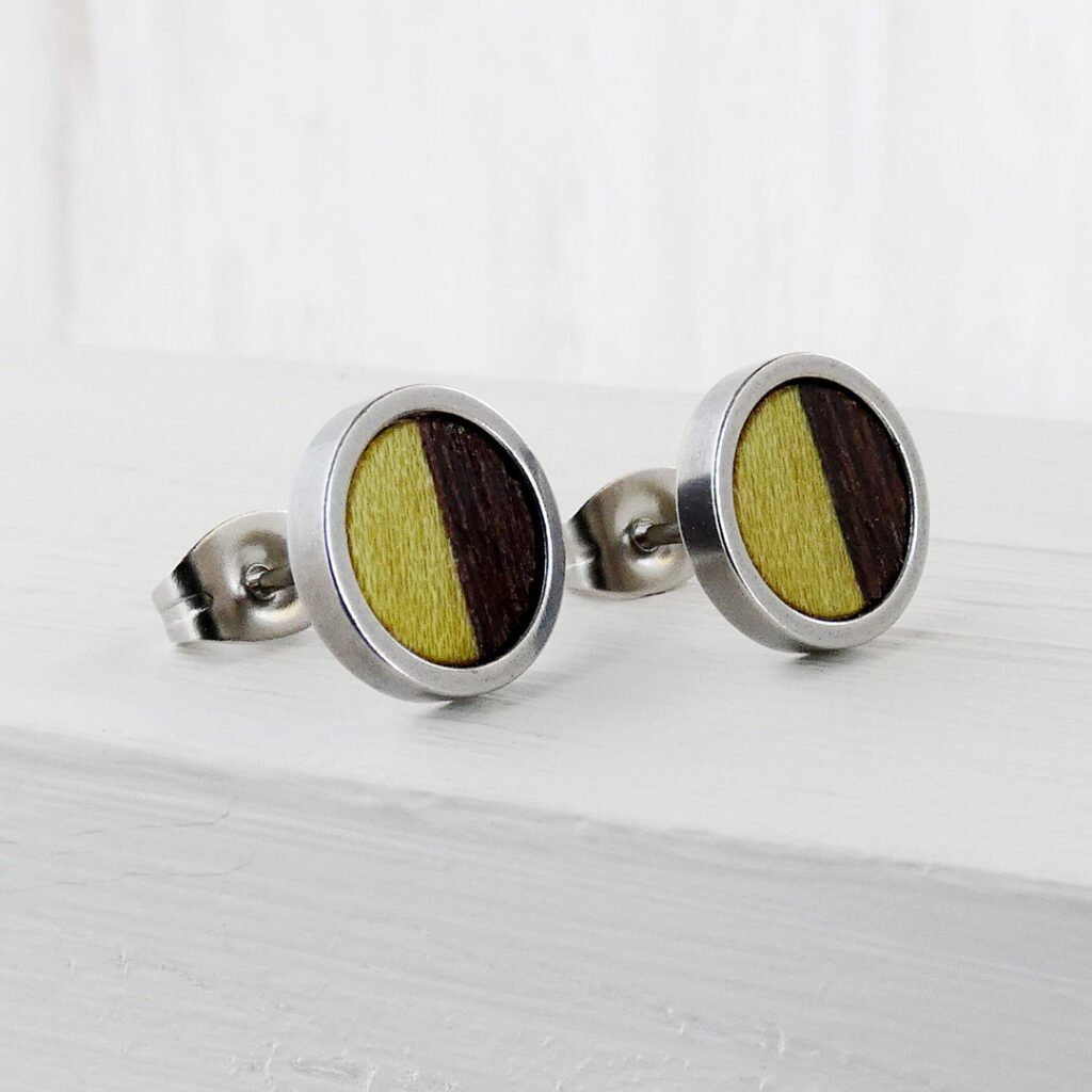 Pendientes de botón redondos de madera bicolor mitad wengué oscuro y mitad madera teñida en verde.