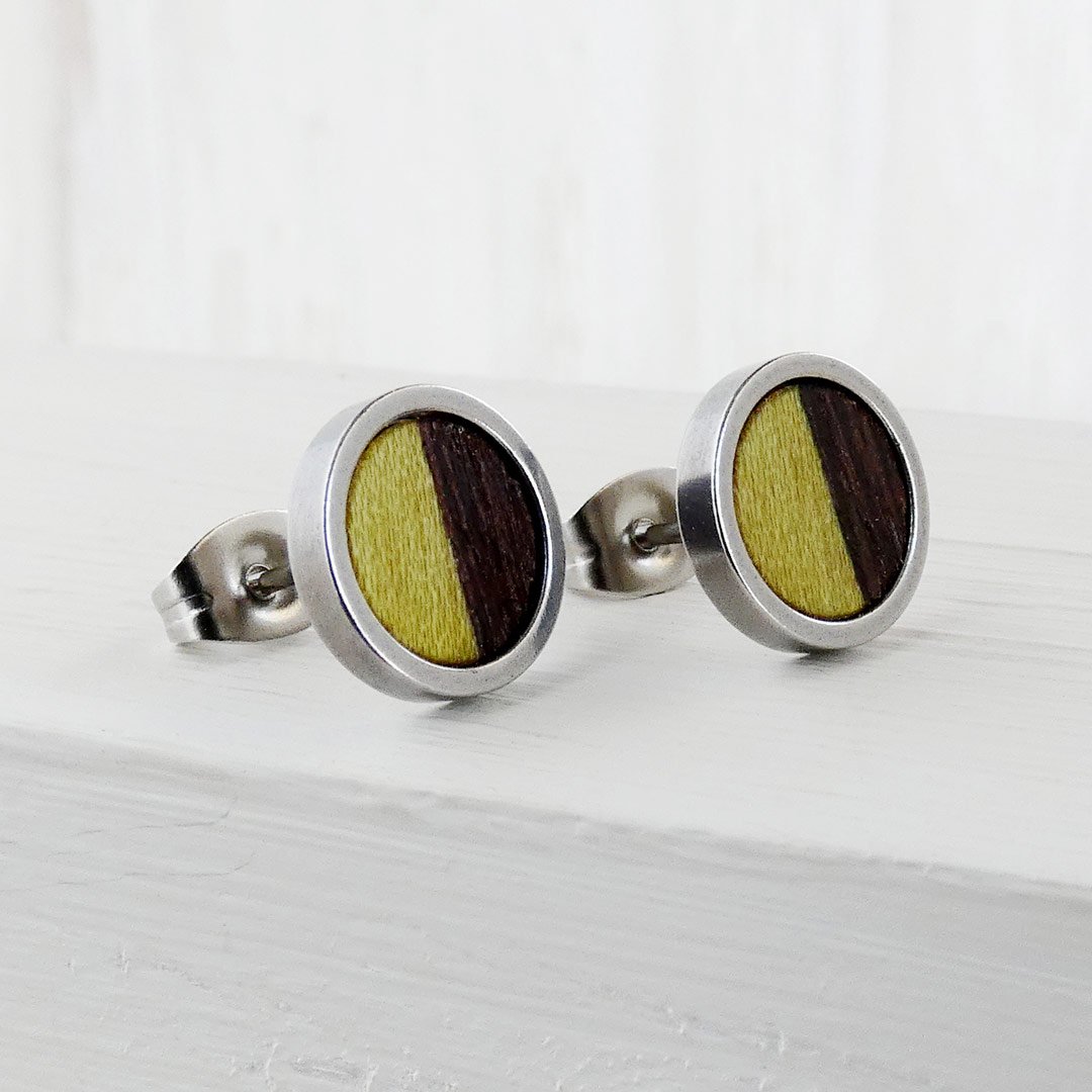 Pendientes de botón redondos de madera bicolor mitad wengué oscuro y mitad madera teñida en verde.