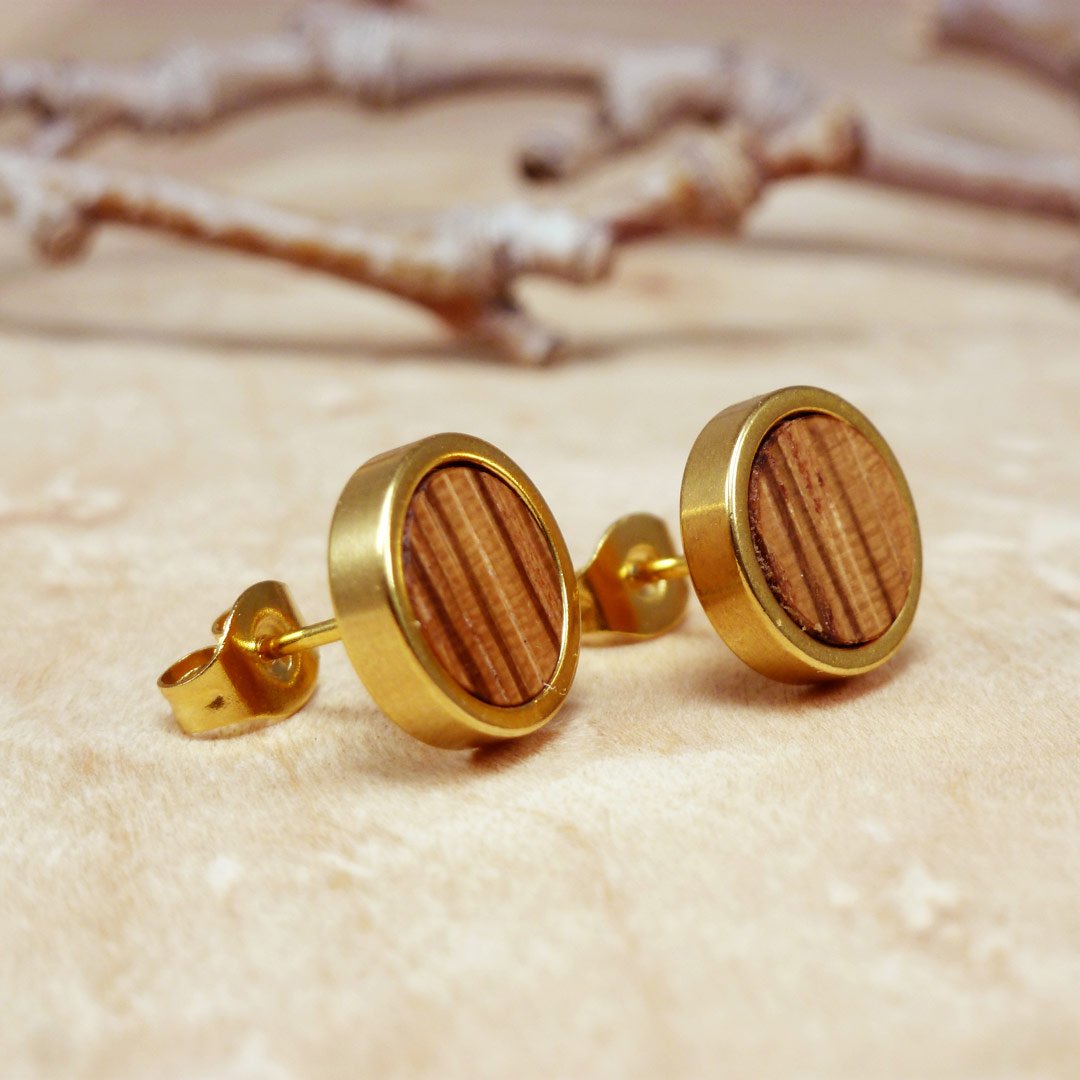 Primer plano de pendientes de zebrano chapados en oro: pendientes rayados hechos a mano