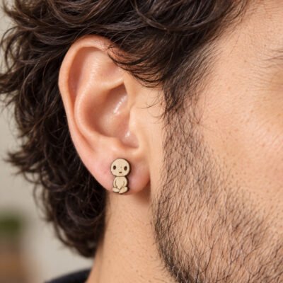 Pendientes pequeños de madera de sicomoro con diseño de Kodama puestos en la oreja de un hombre